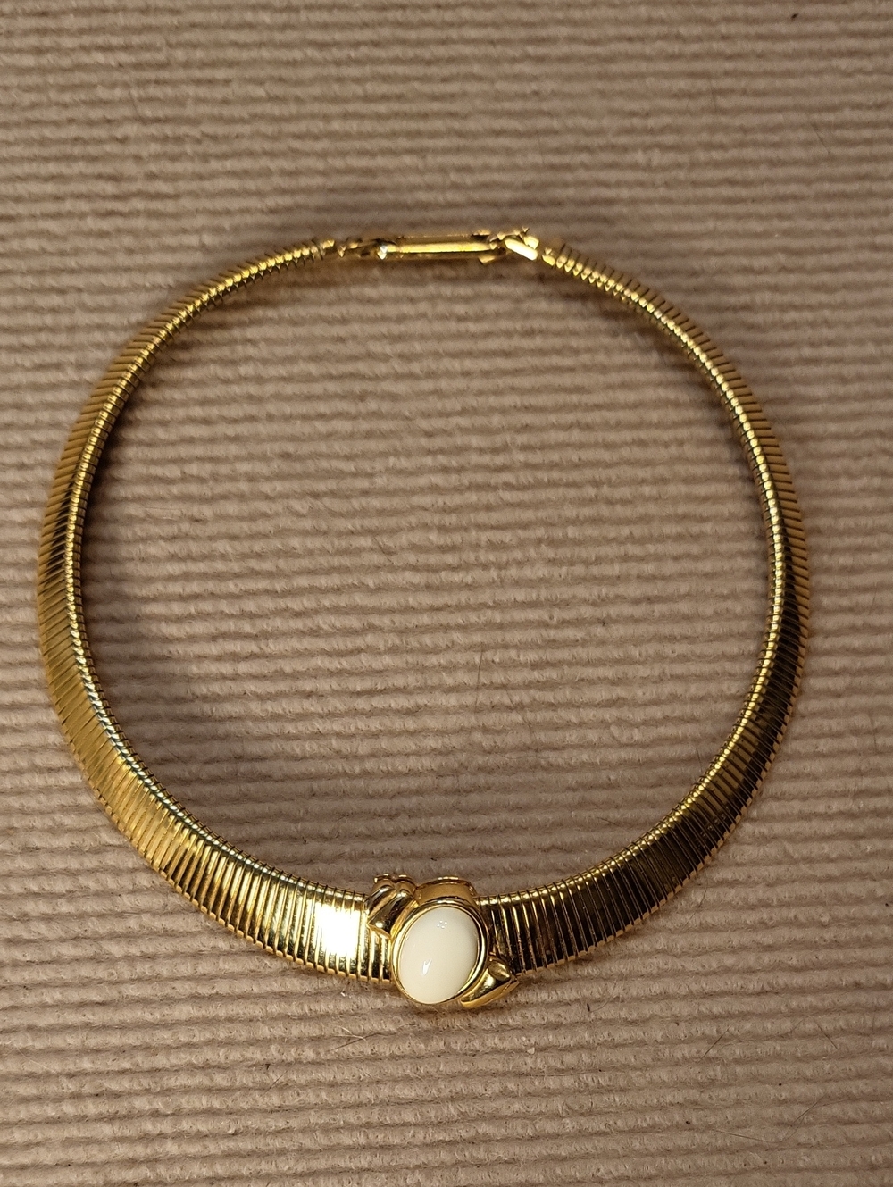 Monet gold-tone omega collar necklace with a cream oval cabochon centerpiece